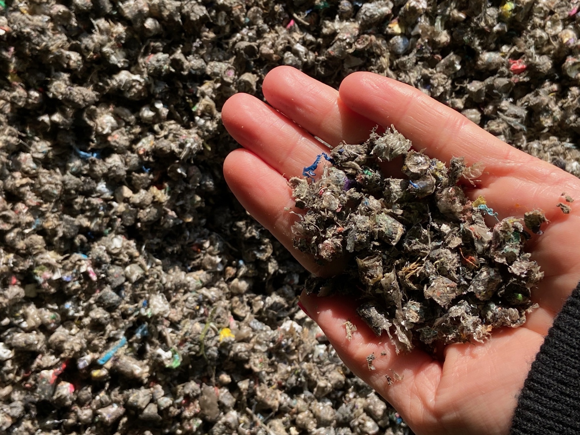 Zerkleinertes Recyclingmaterial in einer Hand – Ausgangsstoff für die Weiterverarbeitung in der Kunststoffaufbereitung oder Ersatzbrennstoffherstellung
