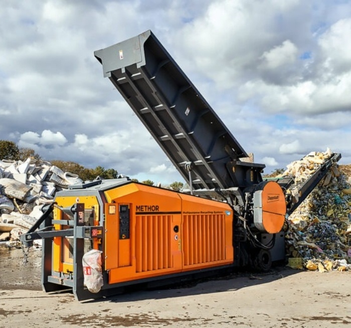 Industriemaschine vor einem Berg Müll mit alten Matratzen und co.