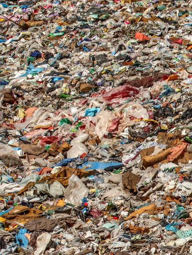 The left section of an image. It shows a pile of plastic waste consisting of bottles, packaging, and plastic film, suitable as material for substitute fuels.